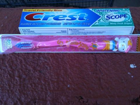 1966 Ford Bronco - A pink toothbrush with a Hello Kitty character and a box of Crest toothpaste are displayed on a textured surface.