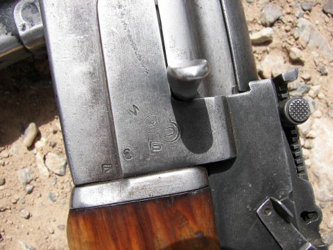 2000 Ford Crown Victoria - Close-up view of a firearm receiver showing Cyrillic markings and a selector switch, with a wooden stock visible.