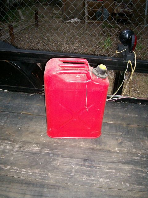 1993 Ford Bronco - A red jerrycan is placed on a trailer, with a fence and vegetation in the background.