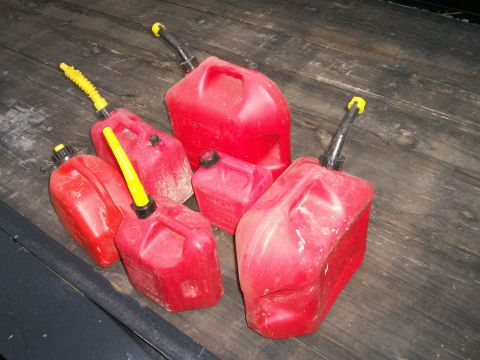 1993 Ford Bronco - A collection of red plastic gas cans are scattered on a wooden deck, some showing signs of wear.