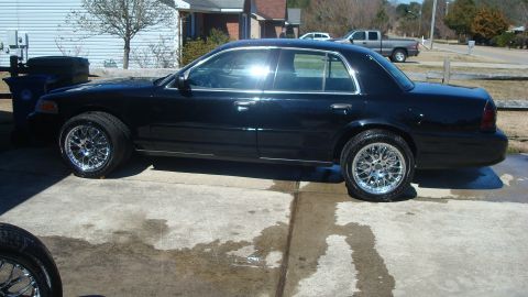 2004 Ford Crown Victoria - A black 2004 Ford Crown Victoria is shown from the side, custom chrome wheels and a clean exterior.