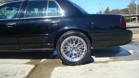 2004 Ford Crown Victoria - Side profile of a black 2004 Ford Crown Victoria custom chrome wheels.