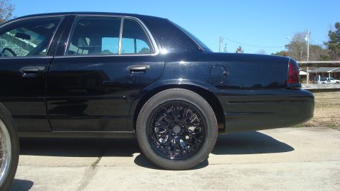 2004 Ford Crown Victoria - A black sedan is shown from the side, custom black wheels and tinted windows.
