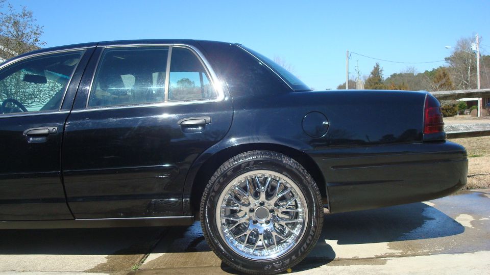 Black sedan, rear quarter view, chrome wheels, aftermarket rims, wet pavement
