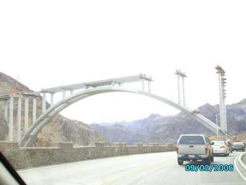 1978 Ford Bronco - Vehicles drive past a large bridge under construction in a mountainous area.