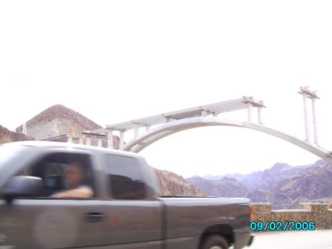 1978 Ford Bronco - A pickup truck passes by a bridge under construction, set against a backdrop of mountains.
