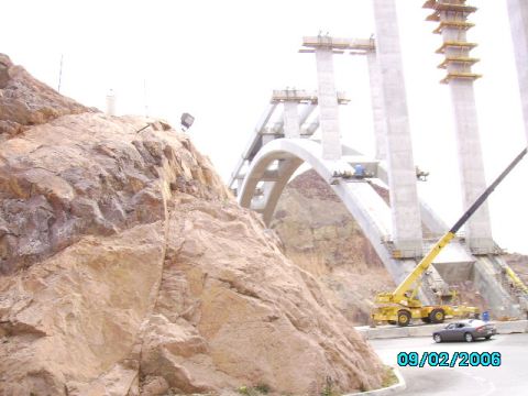 1978 Ford Bronco - A large bridge is under construction, with a crane and a car visible on the road below.
