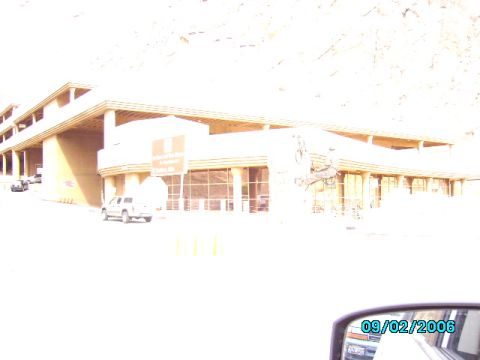 1978 Ford Bronco - A white SUV is parked on the side of the road in front of a large building with many windows.