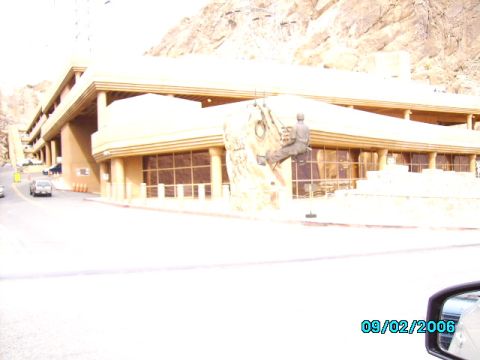 1978 Ford Bronco - A building with a climber statue is seen with cars on the road and mountains in the background.