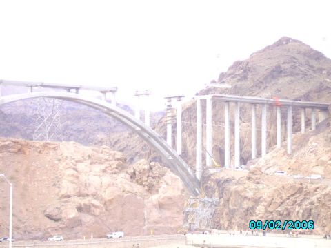 1978 Ford Bronco - A large bridge is under construction, spanning a rocky canyon with a prominent arch and numerous concrete support pillars.