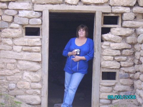 1978 Ford Bronco - A woman stands in the doorway of a rustic stone structure, holding a camera.