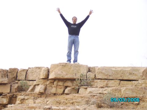 1978 Ford Bronco - Man stands on a rock formation, arms outstretched against a bright sky.