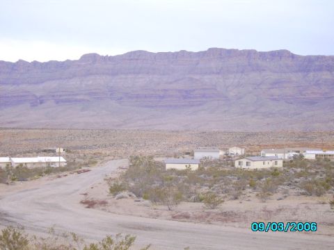 1978 Ford Bronco - A remote desert landscape with several mobile homes is visible under a vast mountain range.