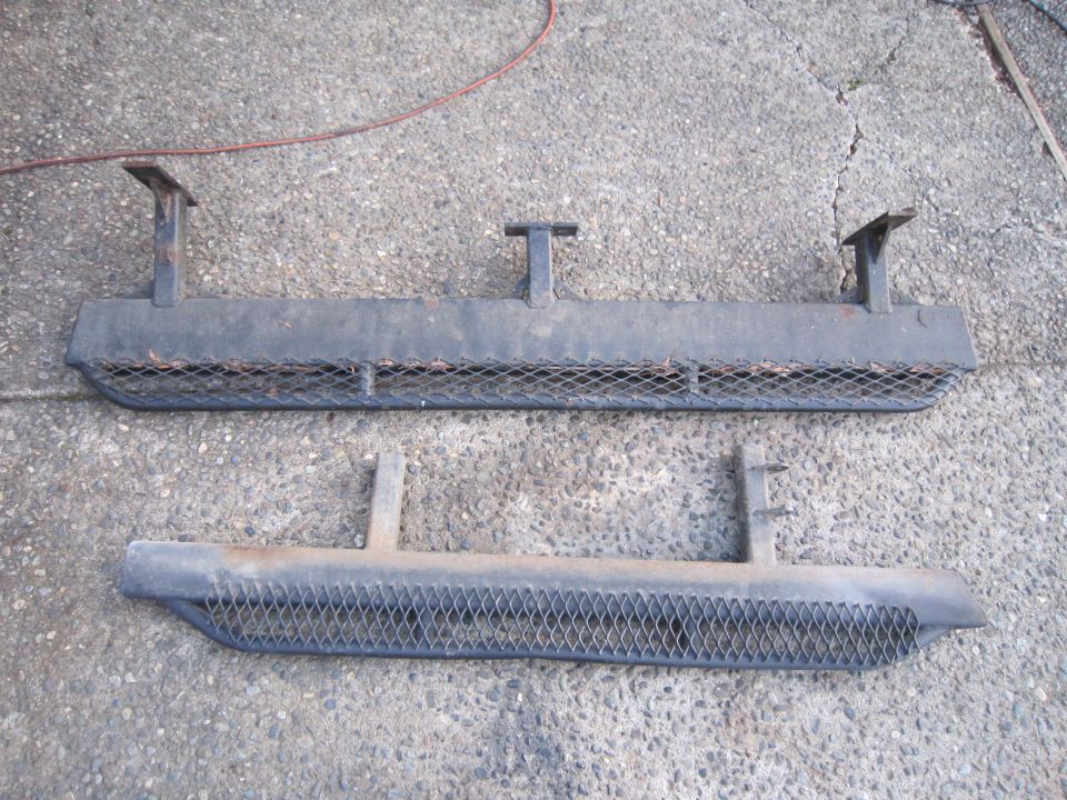 Two black metal running boards with diamond plate inserts, one above the other on concrete