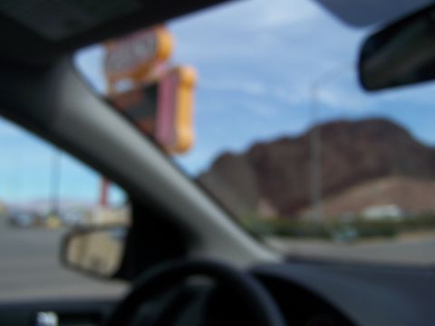 1978 Ford Bronco - Looking out from the driver's seat at a desert scene with mountains and a roadside sign in the distance.