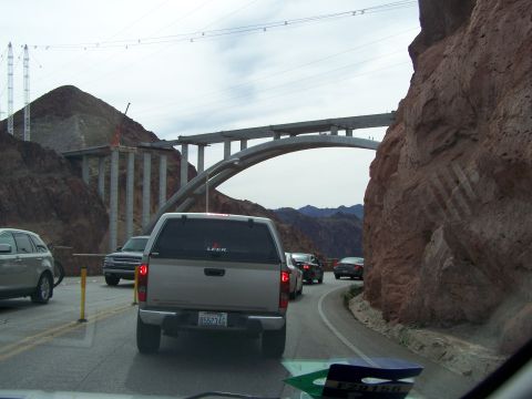 1978 Ford Bronco - Traffic moves along a road near a large bridge construction project, with a silver pickup truck in the foreground.