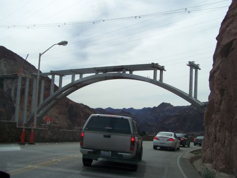 1978 Ford Bronco - Driving past a large bridge construction project with mountains visible beyond the structure.