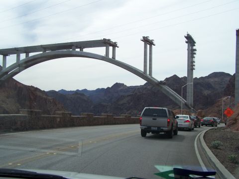 1978 Ford Bronco - Traffic moves along a road with a view of a massive bridge being built across a canyon.