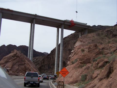 1978 Ford Bronco - Traffic moves along a highway beneath a massive bridge construction project in a rocky, arid landscape.