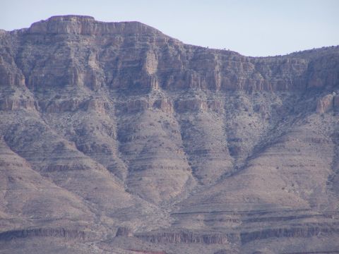 1978 Ford Bronco - A vast mountain range displays distinct horizontal strata, suggesting geological history under a pale blue sky.