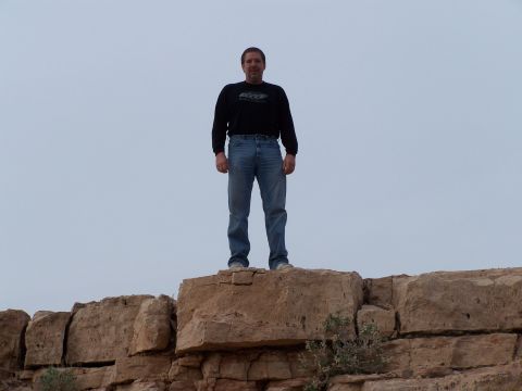 1978 Ford Bronco - A man stands atop a natural rock formation, looking out under an overcast sky.