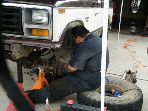 1982 Ford Bronco - A mechanic works on the front suspension of a lifted 1980s Ford Bronco.