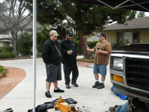 1982 Ford Bronco - A truck's front end is visible as three men converse outdoors.