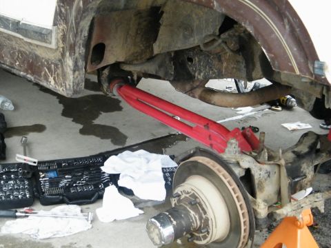1982 Ford Bronco - Close-up view of red suspension components and brake assembly, suggesting a repair or modification in progress.