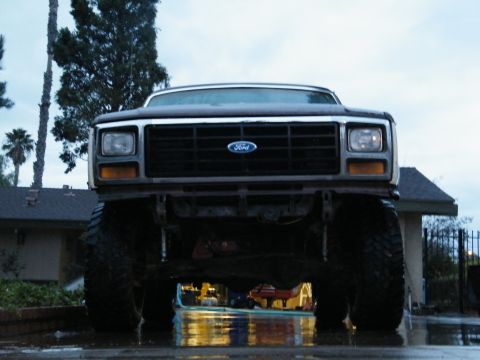 1982 Ford Bronco - A lifted Ford truck sits low to the ground, its front grille and large tires dominating the frame.