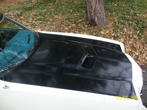 1972 Ford Ranchero - The hood of a white vehicle features a black scoop and a tarp covering the windshield.