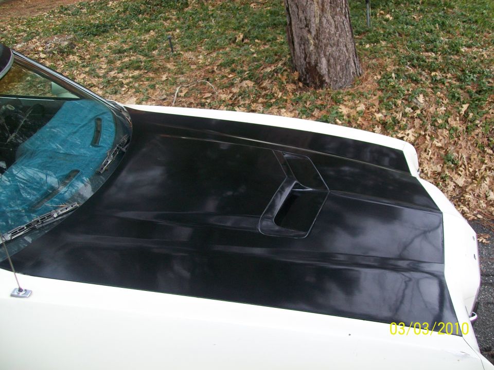 Polished gloss black hood blackout panel with ram-air scoop on a white car