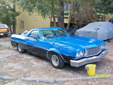 1973 Ford Ranchero - This 1973 Ford Ranchero is parked outside a building with a covered vehicle behind it.