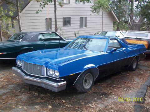 1973 Ford Ranchero - A blue and black Ford Ranchero is parked next to other vehicles, with a house in the background.