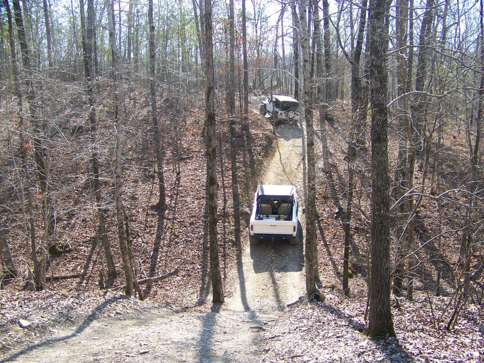 White pickup truck and SUV on a wooded dirt road