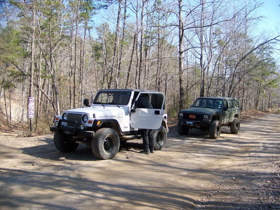 White Jeep Wrangler Rubicon and dark green Jeep Cherokee on a dirt road