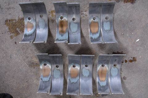 1993 Ford Taurus - Several engine bearing parts are laid out on a concrete surface, showing signs of wear.