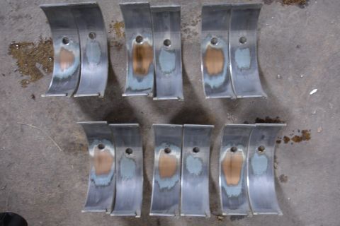 1993 Ford Taurus - Worn engine bearing shells laid out on a concrete surface, showing signs of damage.