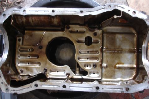 1993 Ford Taurus - Interior view of a used oil pan, showing accumulated oil residue and internal baffles.
