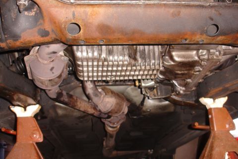 1993 Ford Taurus - The underside of a vehicle is visible, supported by jack stands, with significant rust on the frame components.