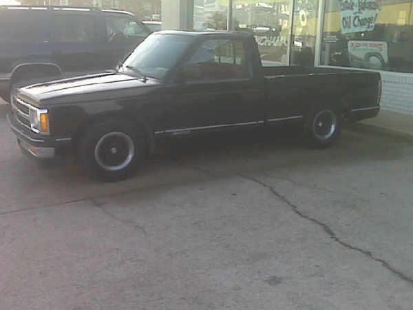 Black lowered Chevrolet S10 regular cab pickup, driver side view, parked outside a shop