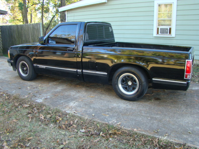 Black lowered pickup truck, rear three-quarter view in a backyard