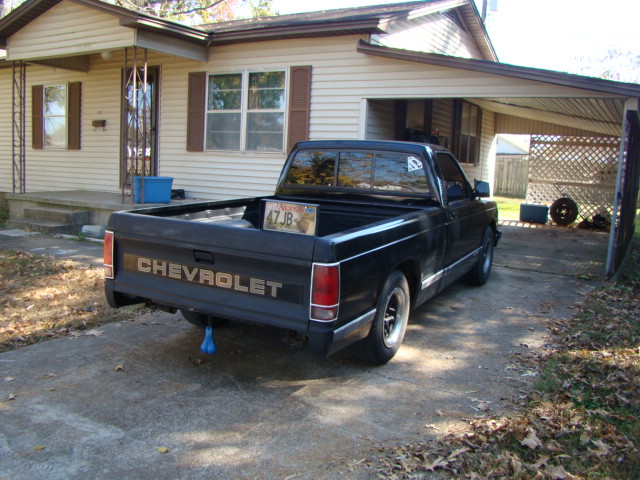 Black Chevrolet compact pickup, rear three-quarter view, parked in driveway with CHEVROLET tailgate lettering