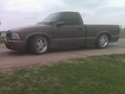 1998 GMC Sonoma - A dark pickup truck is parked on a concrete pad with grass in the foreground.