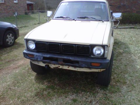 1981 Toyota Hilux - A cream-colored pickup truck is parked on grass, viewed from the front.