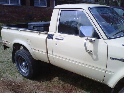 1981 Toyota Hilux - This 1981 Toyota Hilux pickup truck is seen from the side, a cream exterior and a toolbox in the cargo bed.