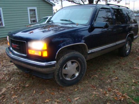 1999 GMC Yukon - This SUV is parked outside on a cloudy day with fallen leaves on the ground.