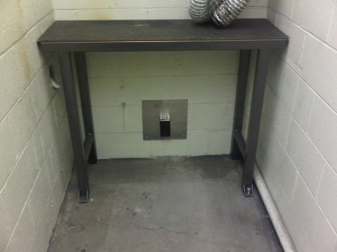 1996 Ford Bronco - A metal table sits in front of a cinder block wall with a vent pipe on top.