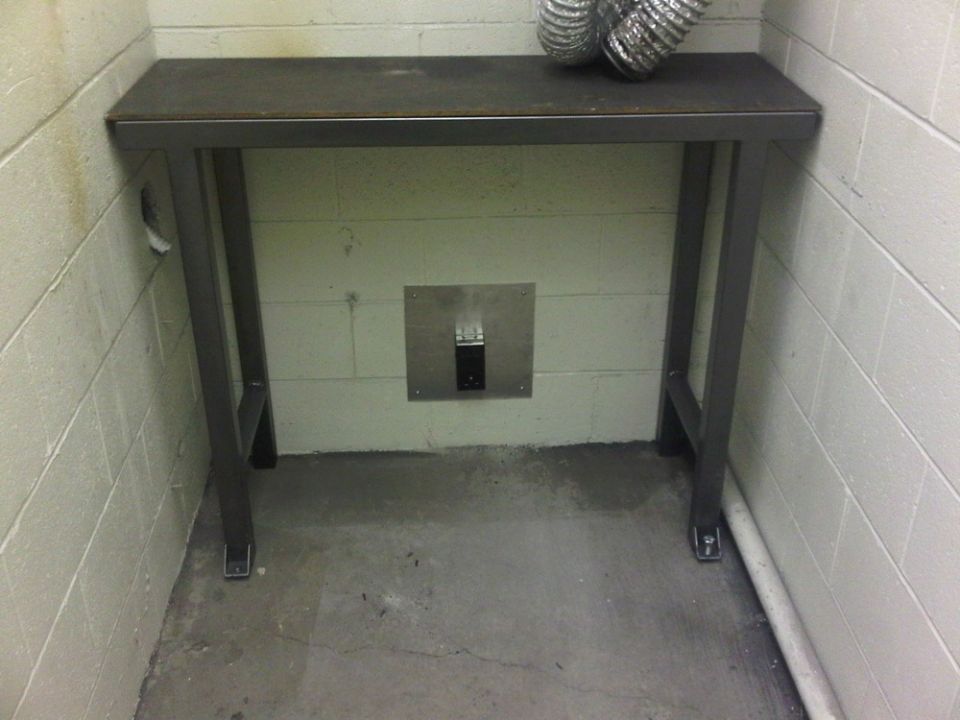 metal table in front of cinder block wall with vent pipe on top