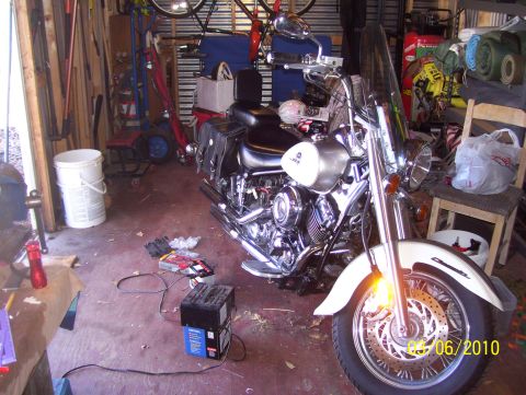 1978 Ford Bronco - Motorcycle sits in a garage filled with various items and equipment.