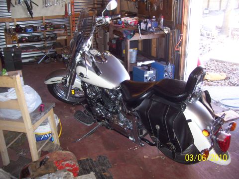 1978 Ford Bronco - Motorcycle with black leather saddlebags parked in a cluttered garage.